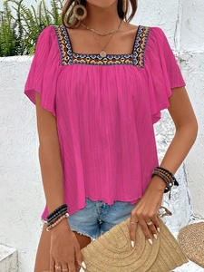 Detail of fuchsia square neck blouse with colorful geometric embroidery and ruffles