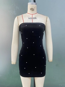 Détails d'une élégante robe moulante noire avec perles blanches et tissu texturé