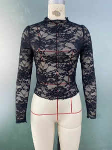 Close-up of black floral lace fabric with see-through texture on a mock neck top