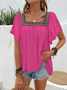 Detailed view of bohemian geometric embroidery on pink square-neck vacation top