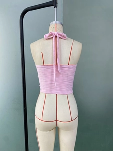 Rear view of pink halter crop top with tie-back design and ribbed texture on mannequin