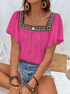 Detailed close-up of geometric ethnic embroidery on fuchsia square neck ruffled blouse