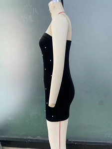 Détail d'une mini robe bustier noire ornée de perles blanches élégantes sur le devant