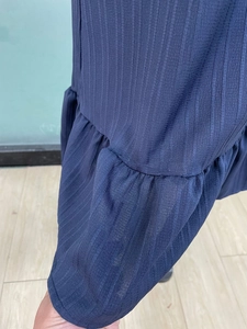 Detail of dark blue sleeveless A-line dress with vertical stripes and ruffled edges