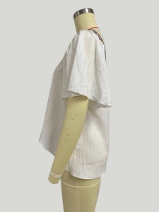 Detail of bohemian embroidery and ruffled sleeve on a white cotton blouse side view