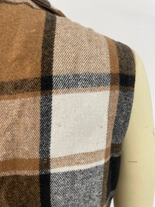 Gros plan sur la texture de laine à carreaux marron et le bouton du gilet élégant