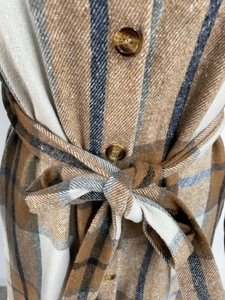 Detail of plaid dress showing thick wool-like fabric texture and amber buttons with tie-belt