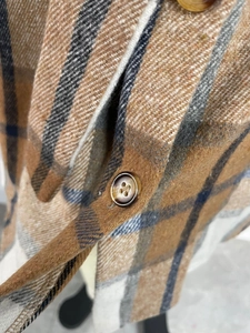 Macro view of plaid fabric texture and resin button on a long-sleeve dress