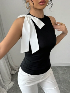 Détail d'un haut noir sans manches élégant avec un grand nœud en satin blanc à l'épaule