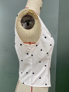 Detail of white sleeveless crop top with black heart print on a dress form mannequin
