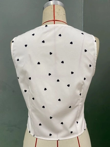 Detail view of the back of a slim-fit white vest with black heart print pattern