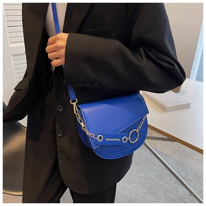 Close-up of royal blue saddle crossbody bag featuring a decorative gold chain detail
