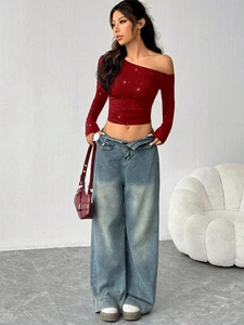 Close-up of asymmetrical off-shoulder long sleeve top with rhinestone glitter details