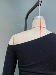 Close-up of black ribbed long sleeve top with silver glitter and off-shoulder neckline