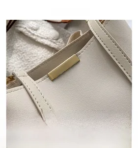 Détail du cuir grainé beige avec surpiqûres précises et plaque métallique dorée brillante