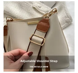 Détail de la bandoulière tissée réglable avec boucle en métal doré sur un sac seau