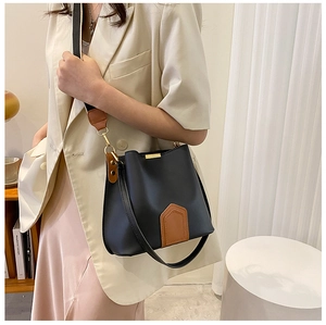 Détail du sac seau noir contrasté avec boucles dorées et bandoulière marron chic