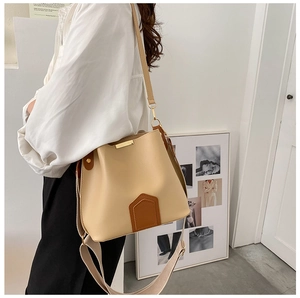 Gros plan du sac seau beige avec garniture en cuir marron et boucles métalliques dorées
