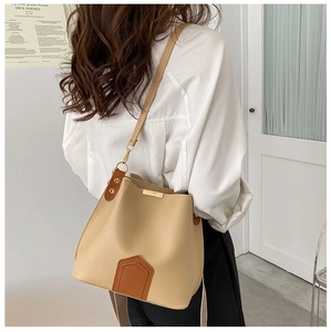 Détail du sac seau beige avec bandoulières marron foncé et fermoir doré