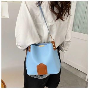 Détail du sac seau bleu clair avec garniture en cuir marron et boucles dorées