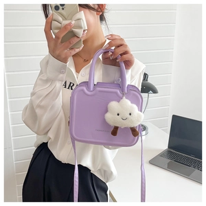 Detail of purple square crossbody bag featuring a plush cloud charm and hand-held strap