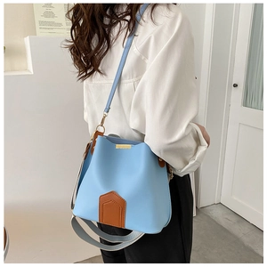 Détail du sac seau bleu clair avec base en cuir marron et doubles bandoulières