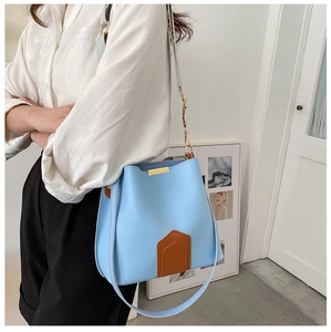 Modèle portant un sac seau bleu clair contrasté avec bordure dorée et doubles bretelles