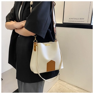 Détail du sac seau contrasté avec bandoulière réglable sur un mannequin en blazer