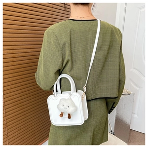 Chic white crossbody bag with cute cloud plush charm shown on person in a cozy interior