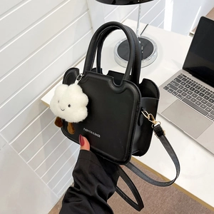 Detail of black crossbody bag with wave edge design and white plush cloud pendant charm