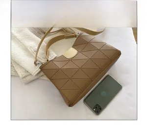 Close-up of brown geometric quilted shoulder bag with phone for size reference
