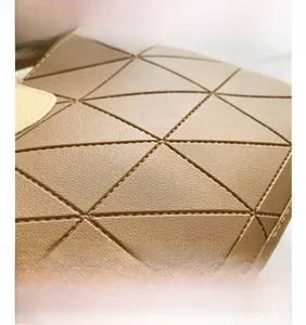Macro view of tan geometric puzzle pieces and high-quality stitching on the bucket bag