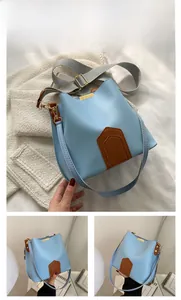 Détail du sac seau bleu clair montrant le cuir grainé et la large bandoulière