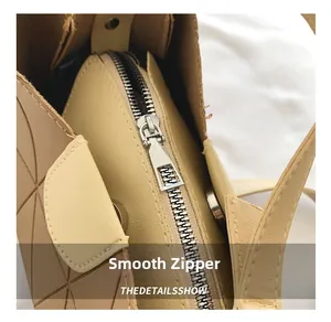Detail of silver smooth metal zipper on khaki and beige quilted fashion bucket bag