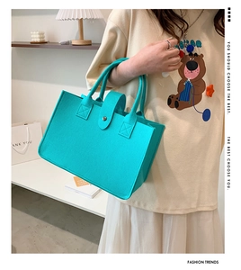 Detail of turquoise felt tote bag featuring a sturdy handle and stylish metal buckle closure