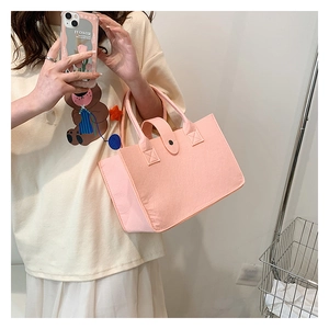 Detail of pink felt tote bag featuring leather snap closure and contrast stitching