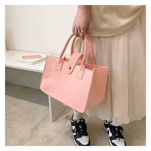 Detail view of pink felt tote bag featuring a secure snap button closure and sturdy handles