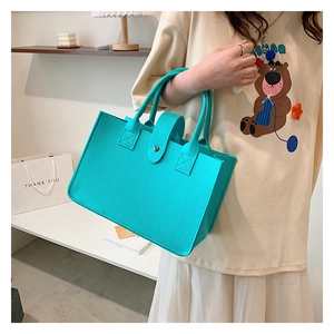 Detailed texture of turquoise felt tote bag with metal snap button closure and handle