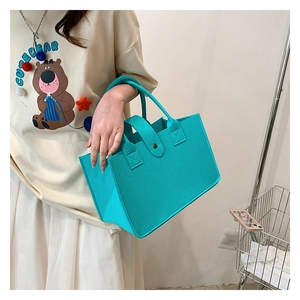 Detailed view of the felt tote bag showing the metal snap button and cross-stitch handles