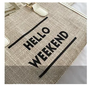 Detail view of khaki canvas tote bag showing the HELLO WEEKEND print and white leather handle