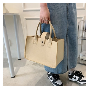 Detail of light beige felt tote bag with metal snap closure shown in a lifestyle setting