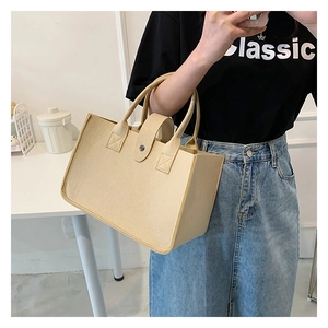 Detail of beige felt tote bag featuring metal buckle strap and sturdy dual handles