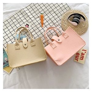 Detail of felt tote bags in khaki and pink showing fiber texture and reinforced stitching