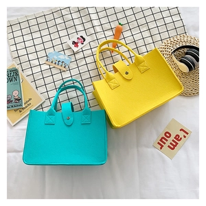 Detail view of colorful felt tote bags with snap buttons in yellow and blue colors
