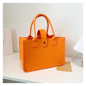 Detail of reinforced stitching and button closure on bright orange felt tote bag