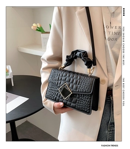 Detail of black crocodile texture handbag with unique cloud pleated handle and gold buckle