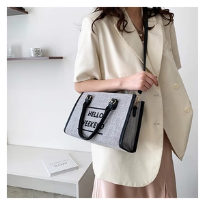 Detail of grey canvas tote bag with black HELLO WEEKEND print and removable shoulder strap