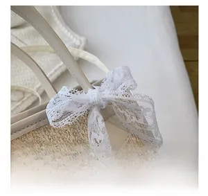 Détail du nœud en dentelle blanche et de la texture tissée d'un sac paille vintage