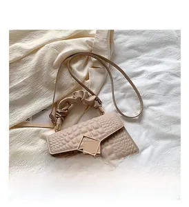 Gros plan sur la poignée plissée et le cuir crocodile du petit sac carré kaki