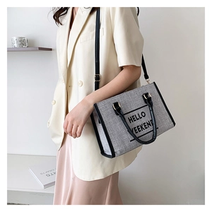 Detail of grey canvas tote bag with HELLO WEEKEND print and black leather handles